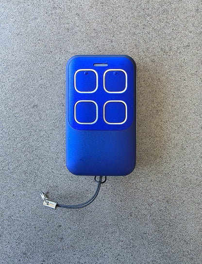 Blue remote control with four buttons on a gray surface