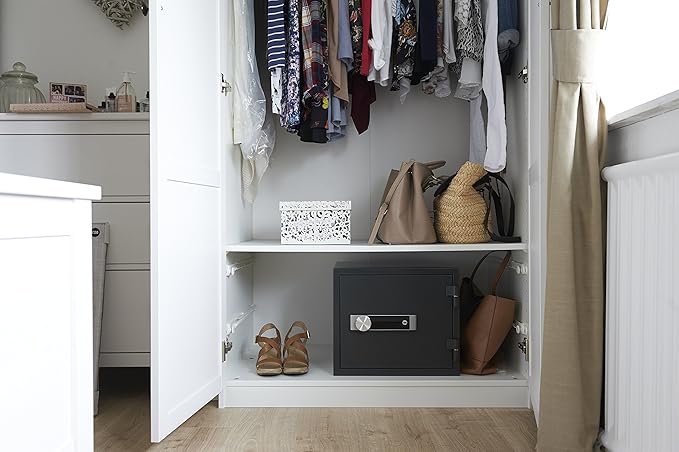 Open wardrobe with clothes, bags, and a safe inside