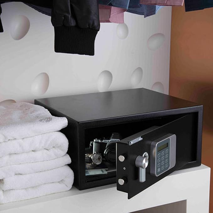 Black safe box on a white shelf with towels and clothes in the background