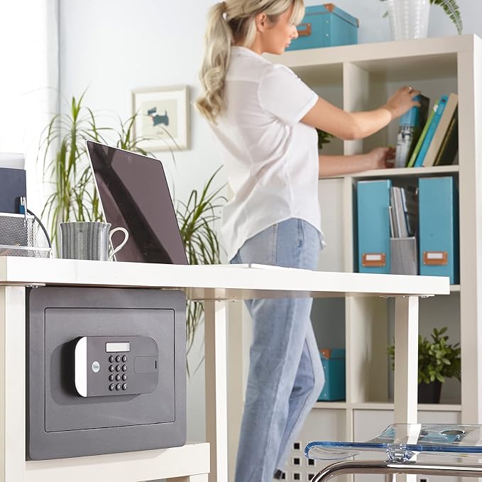 Person organizing items on a desk with a safe box underneath