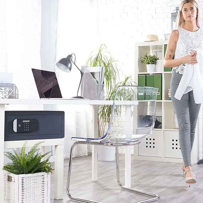 Woman standing in a modern office with a desk, chair, and safe.