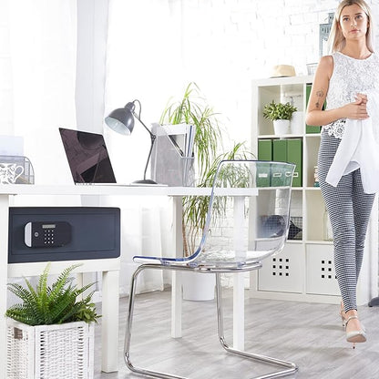 Woman standing in a modern office with a desk, chair, and safe.