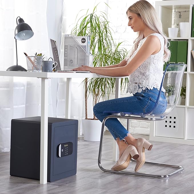 Woman sitting at a desk with a laptop, next to a black safe box.