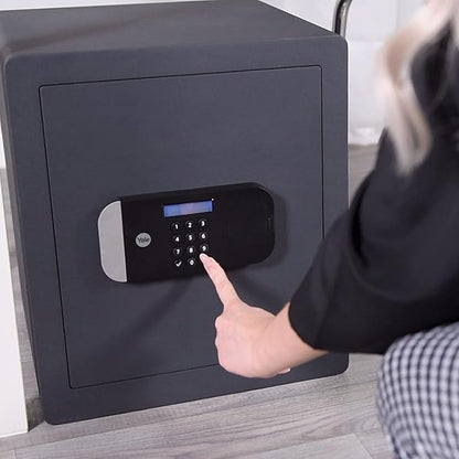 Person using a digital keypad on a black safe box.