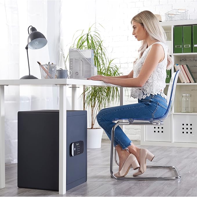 Woman sitting at a desk with a black security safe box next to her.