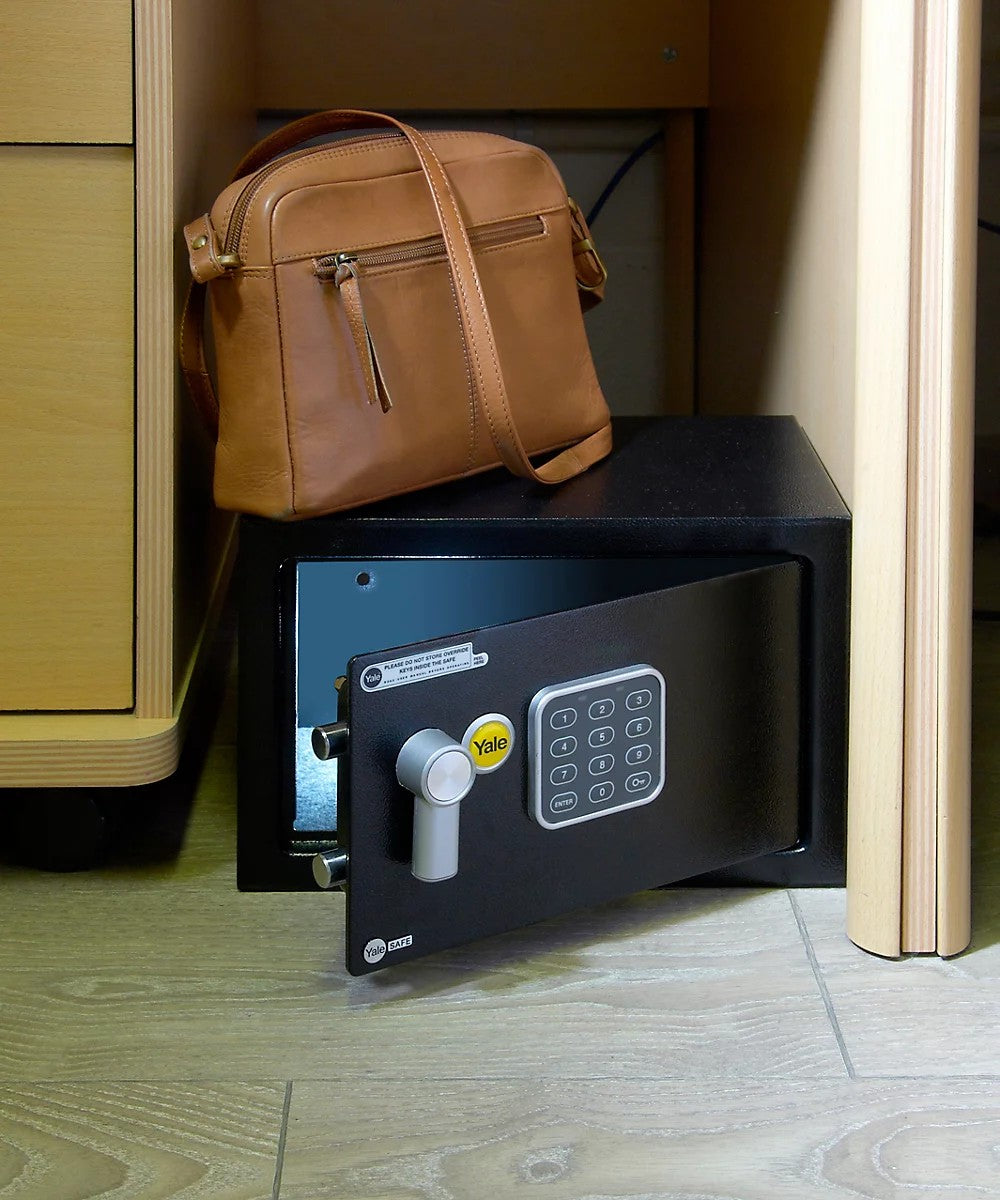 Yale medium safe open on floor amongst shelves & drawers with bag on top